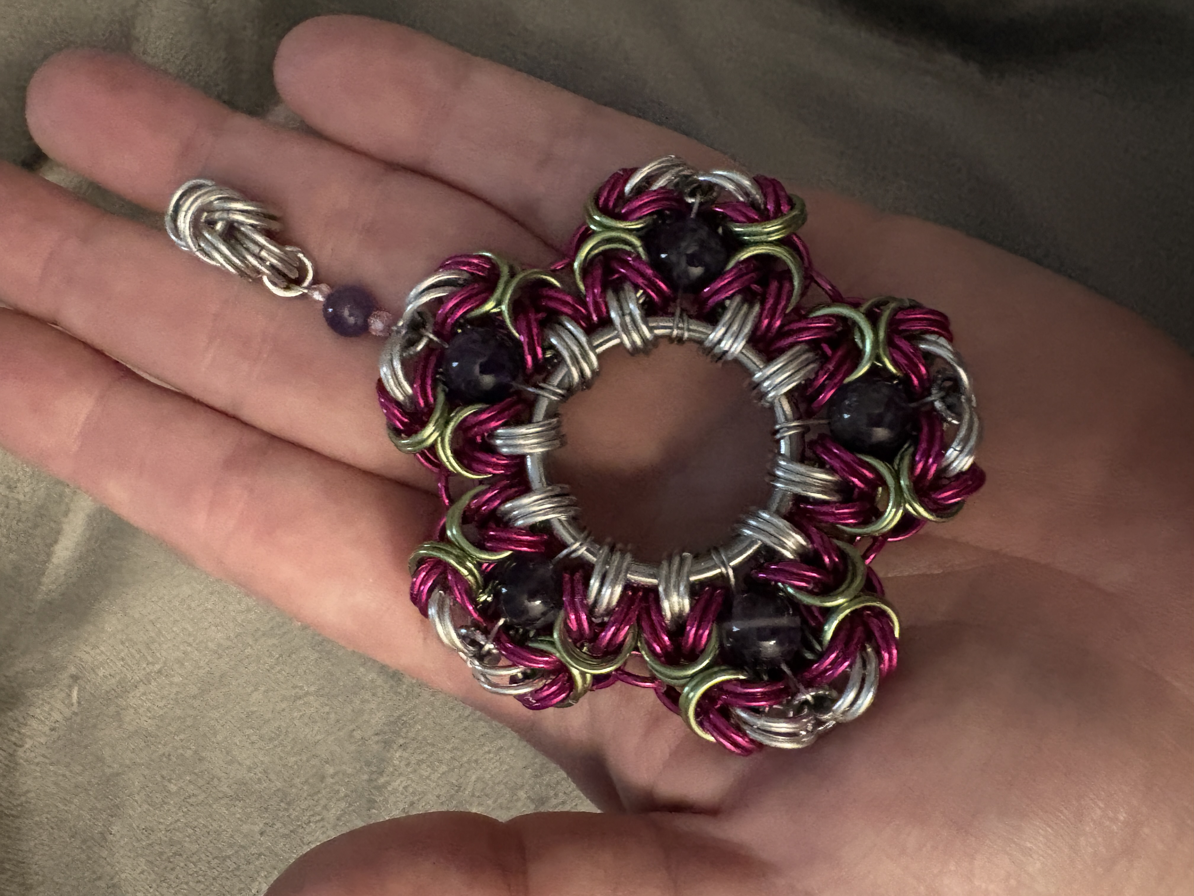 Silver chainmaille necklace with a dark blue pendant.